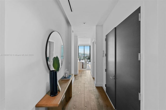 corridor featuring wood-type flooring and baseboards