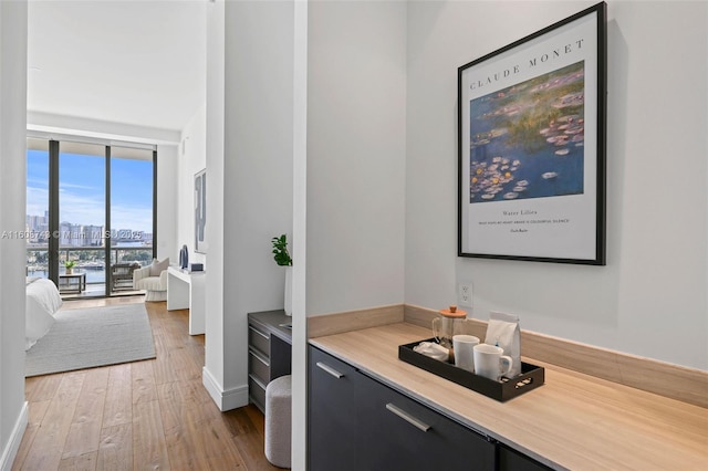 bar featuring a view of city, baseboards, hardwood / wood-style flooring, and floor to ceiling windows