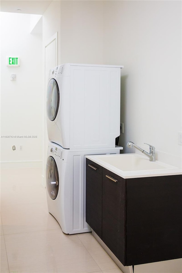 laundry room with a sink, stacked washing maching and dryer, light tile patterned floors, and cabinet space