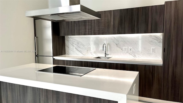 kitchen featuring tasteful backsplash, island exhaust hood, sink, and kitchen peninsula