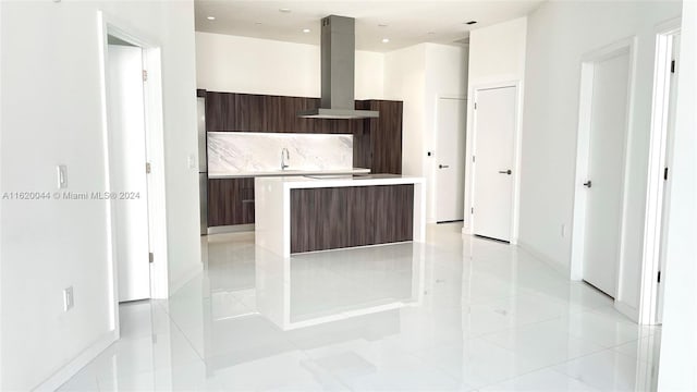 kitchen with dark brown cabinetry, sink, island range hood, a center island, and backsplash