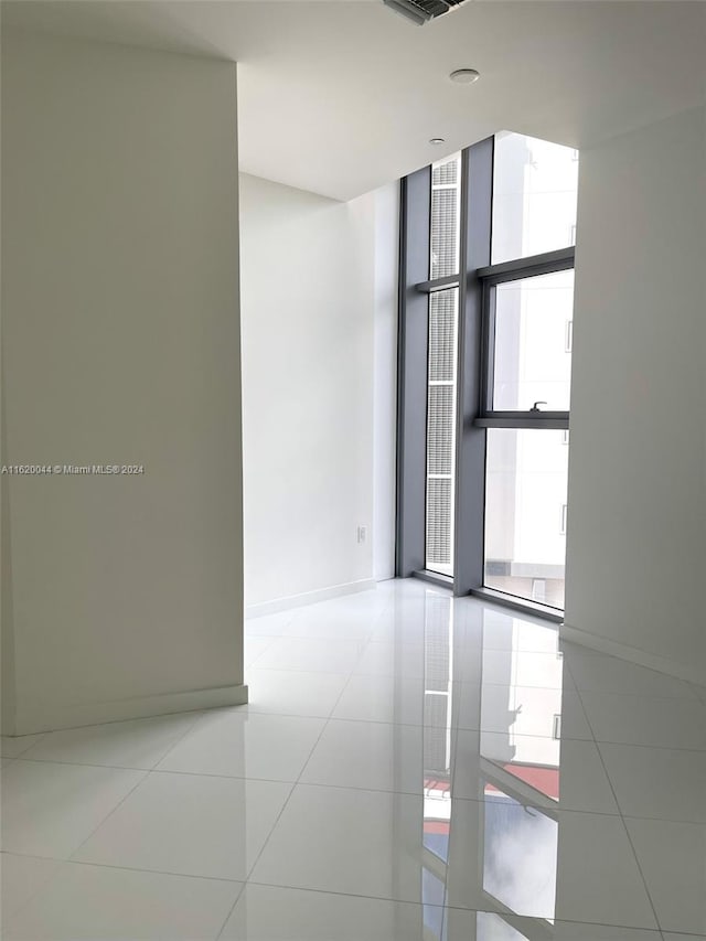 tiled empty room featuring floor to ceiling windows