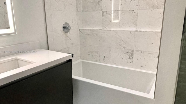 bathroom featuring tiled shower / bath combo and vanity