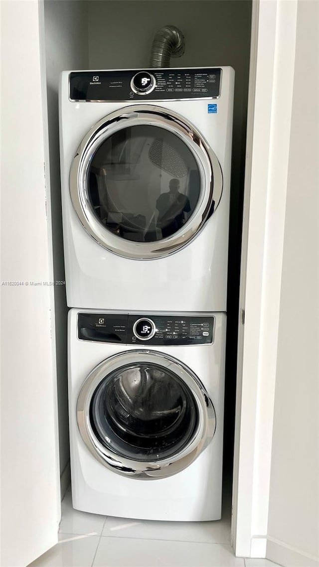 clothes washing area with tile patterned floors and stacked washer / dryer