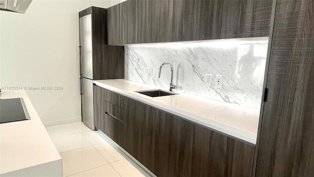 kitchen featuring light tile patterned flooring, dark brown cabinets, sink, and decorative backsplash