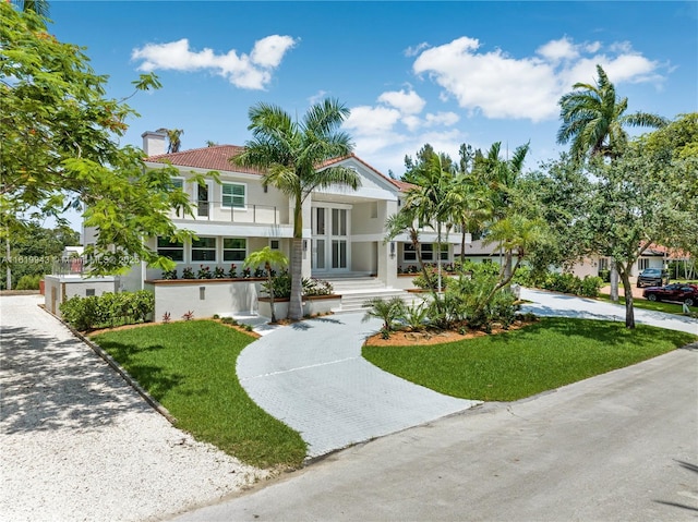 view of front of home with a front yard, french doors, and a balcony