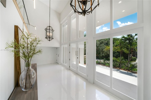 interior space with tile patterned floors, a wealth of natural light, a chandelier, and a towering ceiling