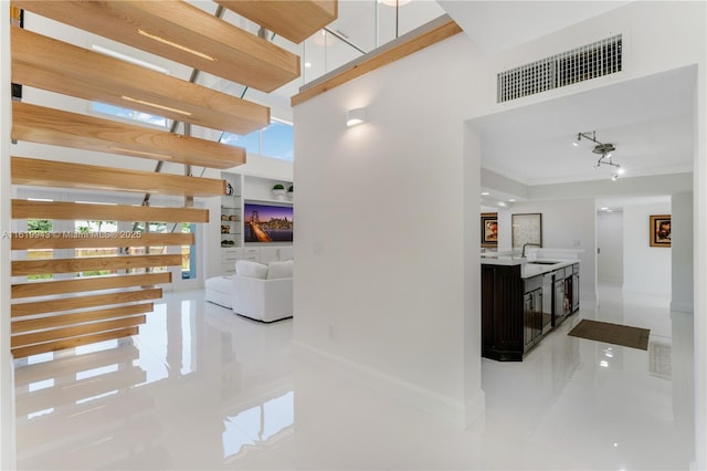 hall featuring sink, tile patterned floors, a wealth of natural light, and crown molding