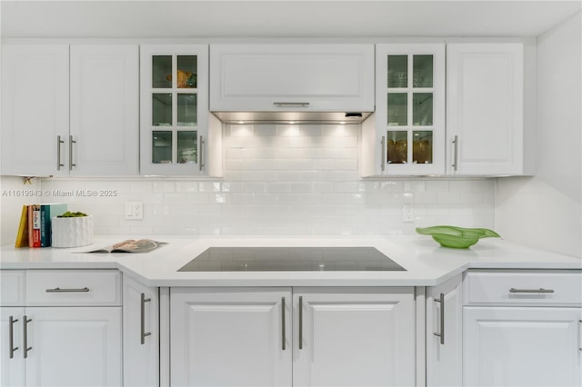 kitchen featuring decorative backsplash, black electric cooktop, and white cabinetry