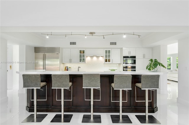 kitchen featuring tasteful backsplash, white cabinets, a large island, and appliances with stainless steel finishes