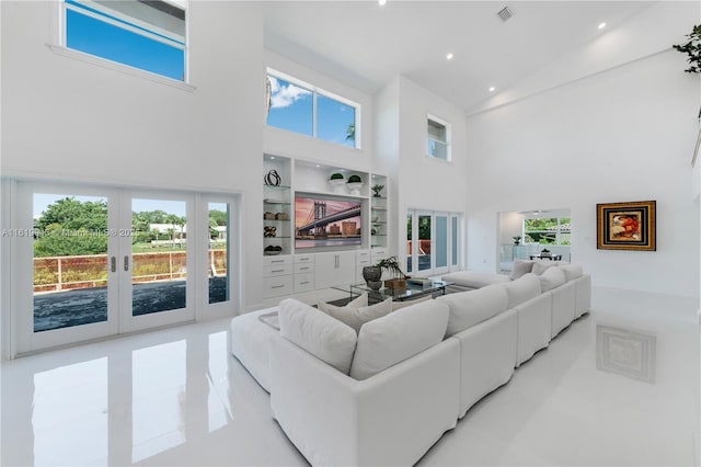 living room featuring french doors, built in shelves, a towering ceiling, and light tile patterned flooring