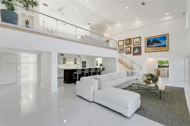 living room featuring ceiling fan, concrete flooring, and high vaulted ceiling