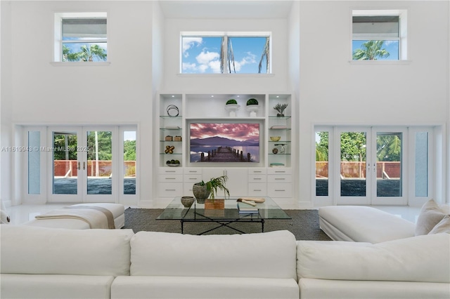 living room featuring french doors, a towering ceiling, and plenty of natural light