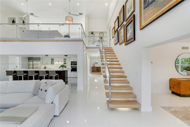 living room featuring ceiling fan and a high ceiling