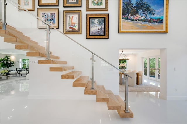 staircase featuring french doors and an inviting chandelier