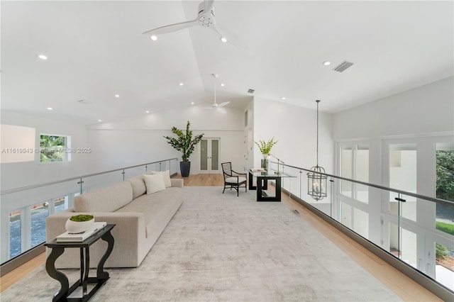 living room featuring high vaulted ceiling, ceiling fan with notable chandelier, and light hardwood / wood-style flooring