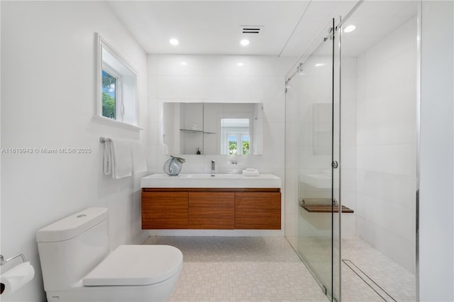 bathroom featuring toilet, vanity, and a shower with door