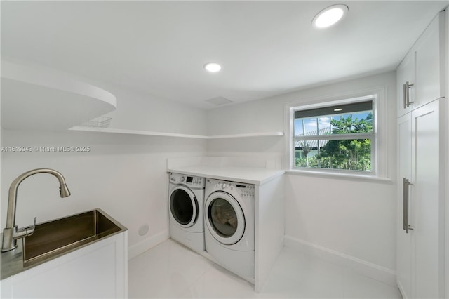 washroom with cabinets, sink, and washing machine and dryer