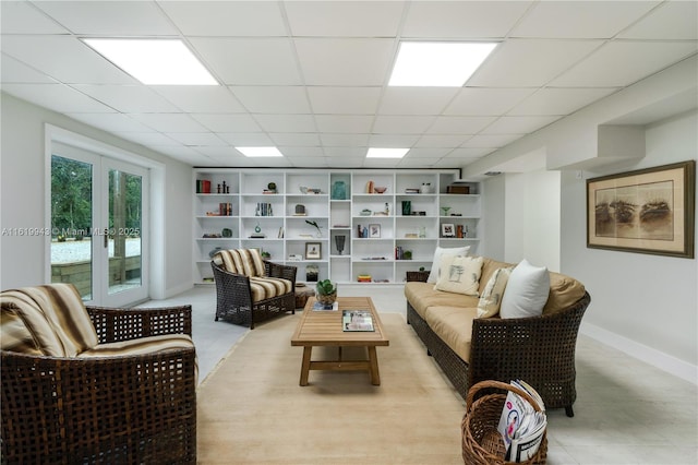 living area with a drop ceiling, built in features, and french doors