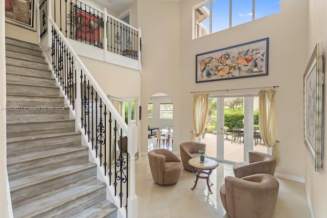 living room featuring french doors, light tile patterned floors, and a high ceiling