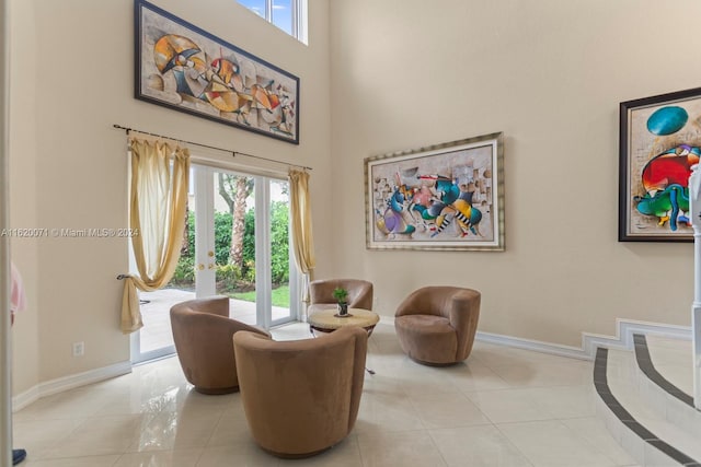 sitting room with a wealth of natural light, tile patterned flooring, and a towering ceiling