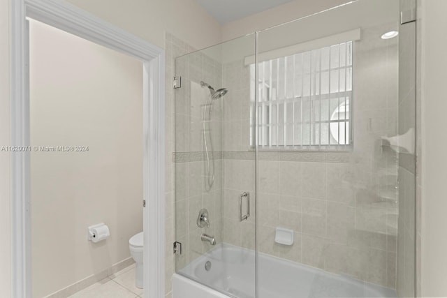 bathroom with tile patterned floors, bath / shower combo with glass door, and toilet