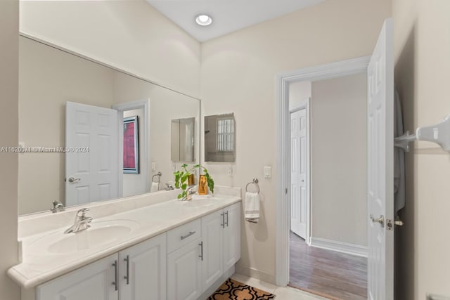 bathroom with double vanity and hardwood / wood-style floors