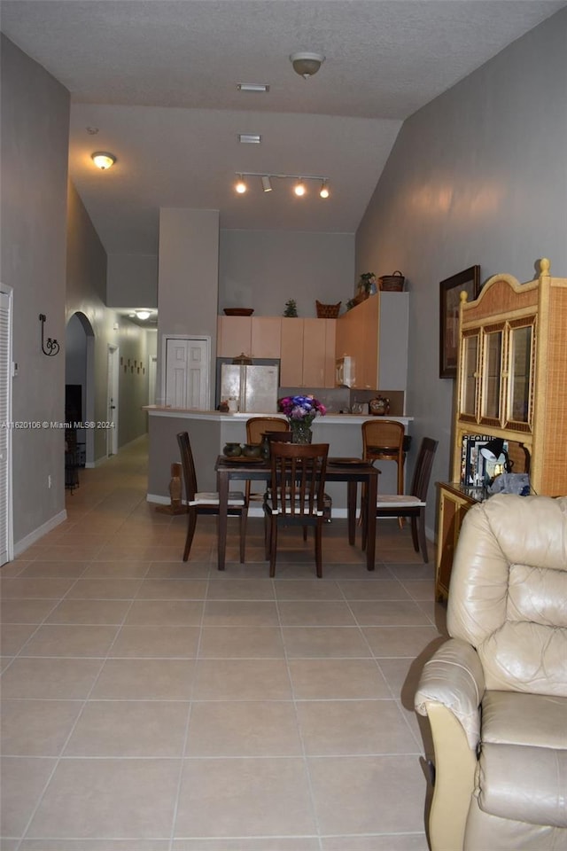 dining area featuring light tile patterned floors and high vaulted ceiling