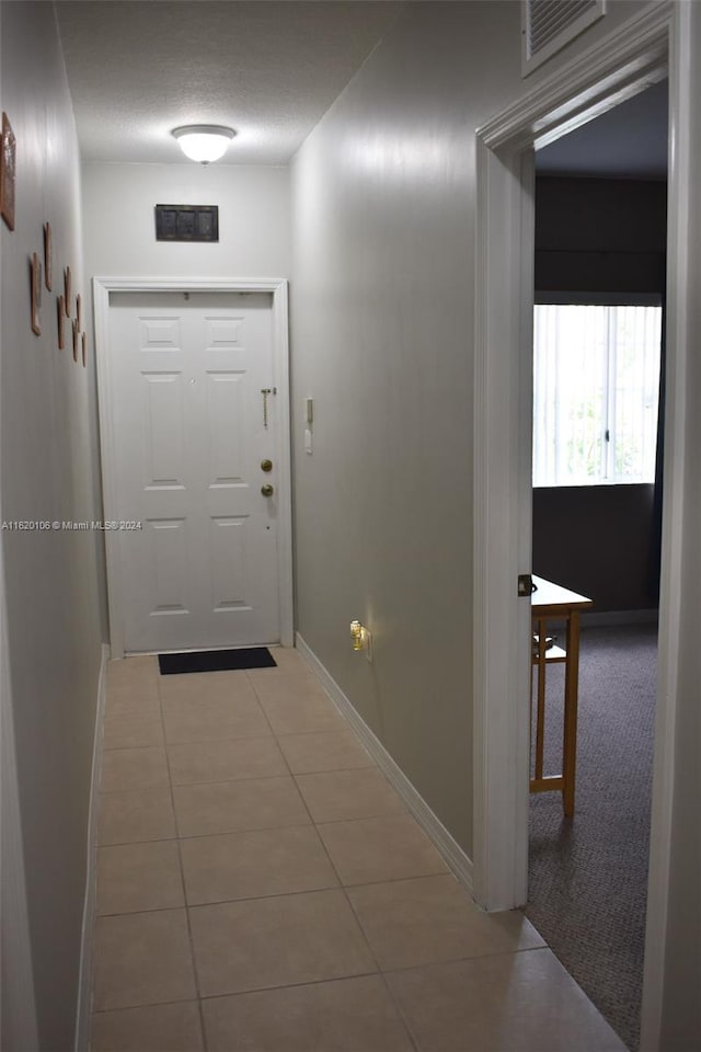 doorway featuring a textured ceiling and tile patterned flooring