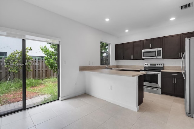 kitchen featuring plenty of natural light, stainless steel appliances, dark brown cabinets, and kitchen peninsula