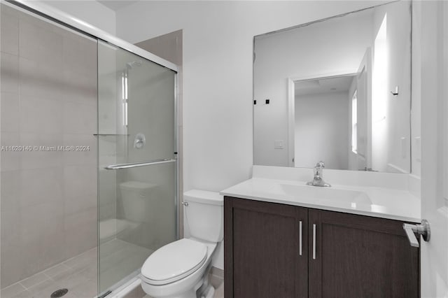 bathroom with a shower with door, vanity, and toilet