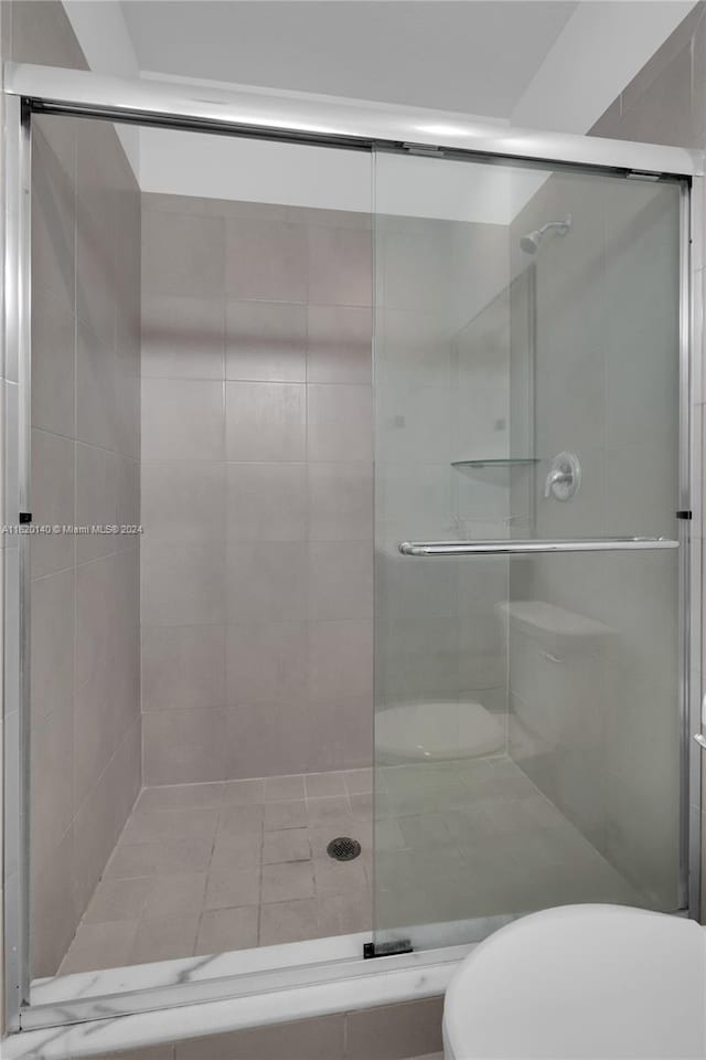 bathroom with a shower with door and toilet