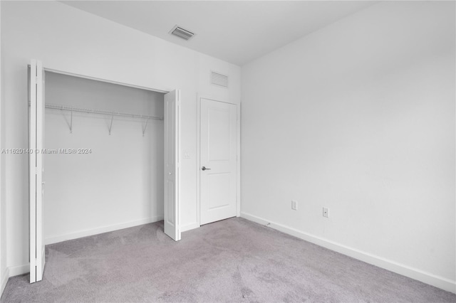 unfurnished bedroom featuring light carpet and a closet