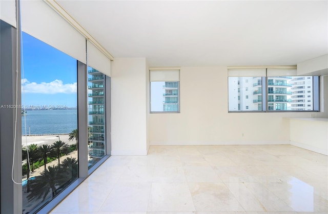 unfurnished room featuring a water view, a wealth of natural light, and tile patterned flooring