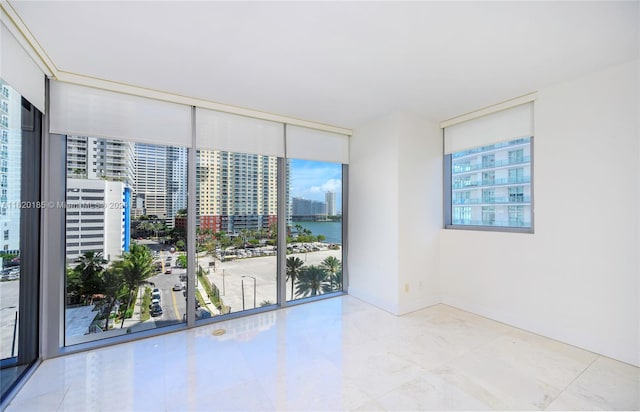 unfurnished room with a water view, floor to ceiling windows, a healthy amount of sunlight, and light tile patterned floors