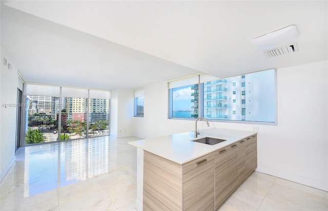 kitchen featuring light tile patterned floors, a healthy amount of sunlight, light brown cabinetry, and sink