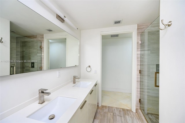 bathroom featuring dual vanity, a shower with shower door, and tile patterned flooring