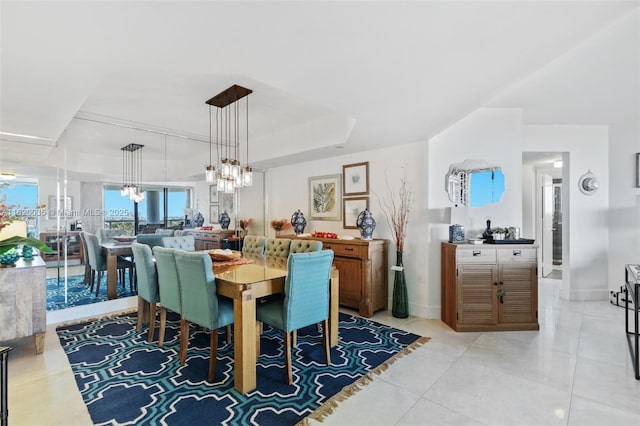 dining space featuring a notable chandelier, a raised ceiling, and light tile patterned floors