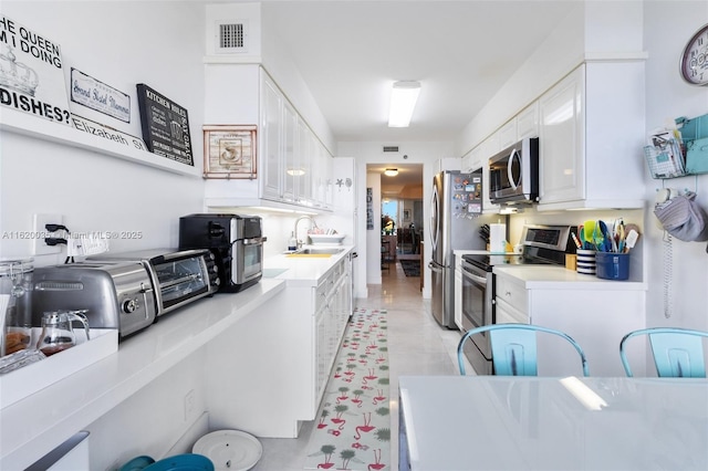 kitchen featuring stainless steel appliances, sink, and white cabinets