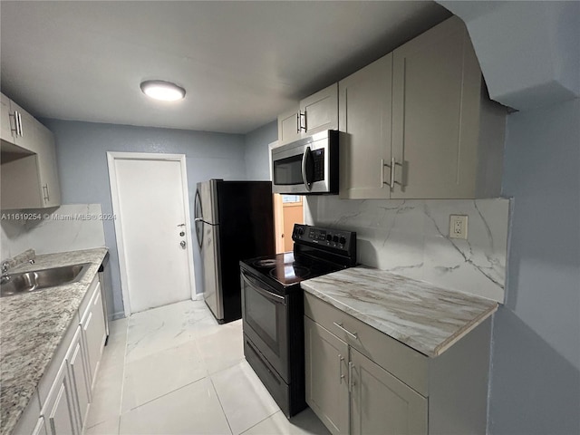 kitchen featuring backsplash, stainless steel appliances, gray cabinets, and sink