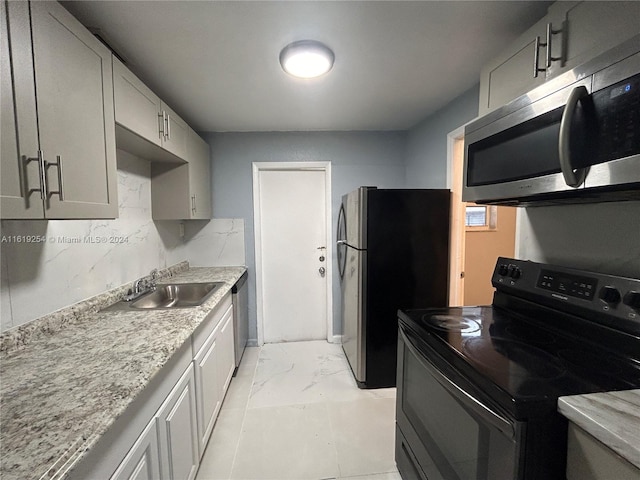 kitchen with light stone countertops, stainless steel appliances, tasteful backsplash, and sink