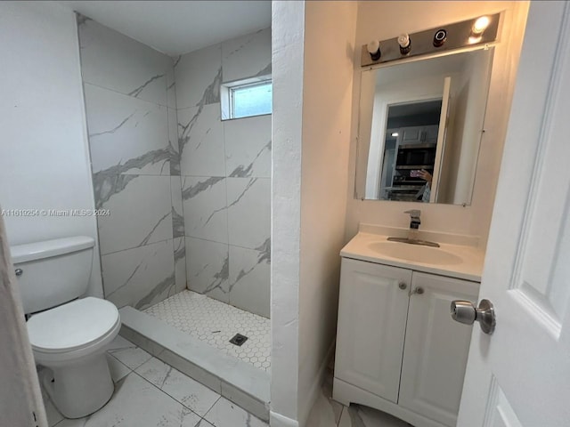 bathroom with vanity, toilet, and tiled shower