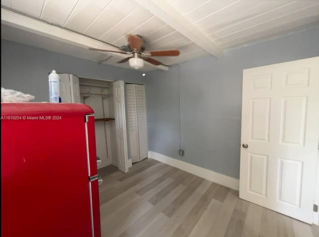 unfurnished bedroom with light wood-type flooring, refrigerator, ceiling fan, and beamed ceiling