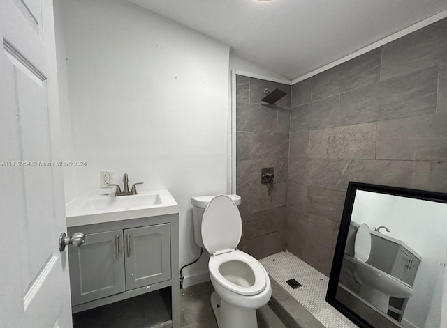 bathroom with tiled shower, vanity, and toilet