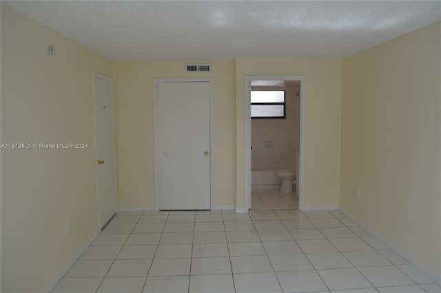 tiled empty room with a textured ceiling