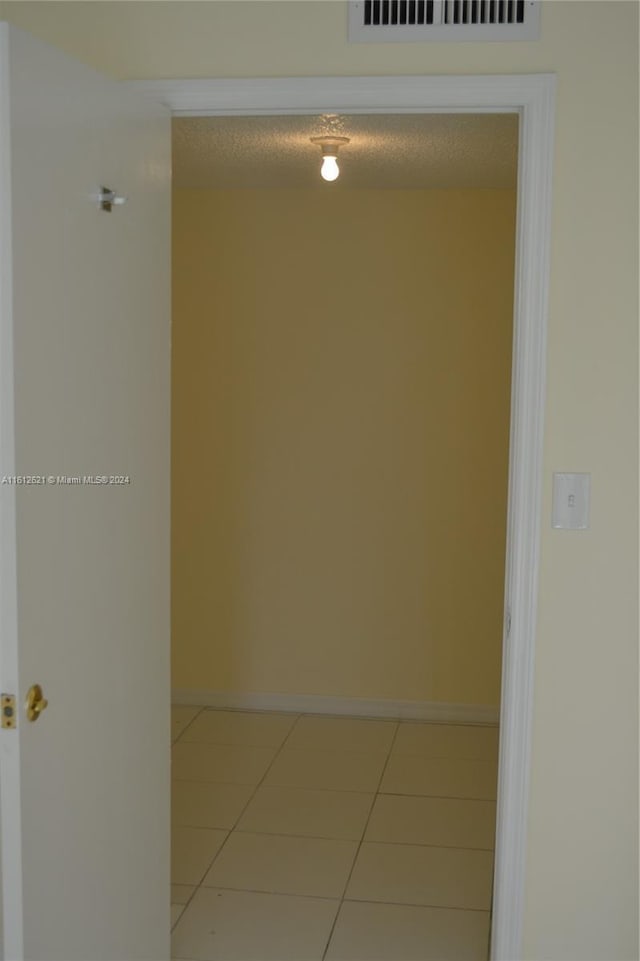 hallway with tile patterned flooring and a textured ceiling