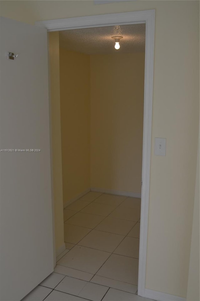 hall with light tile patterned floors and a textured ceiling