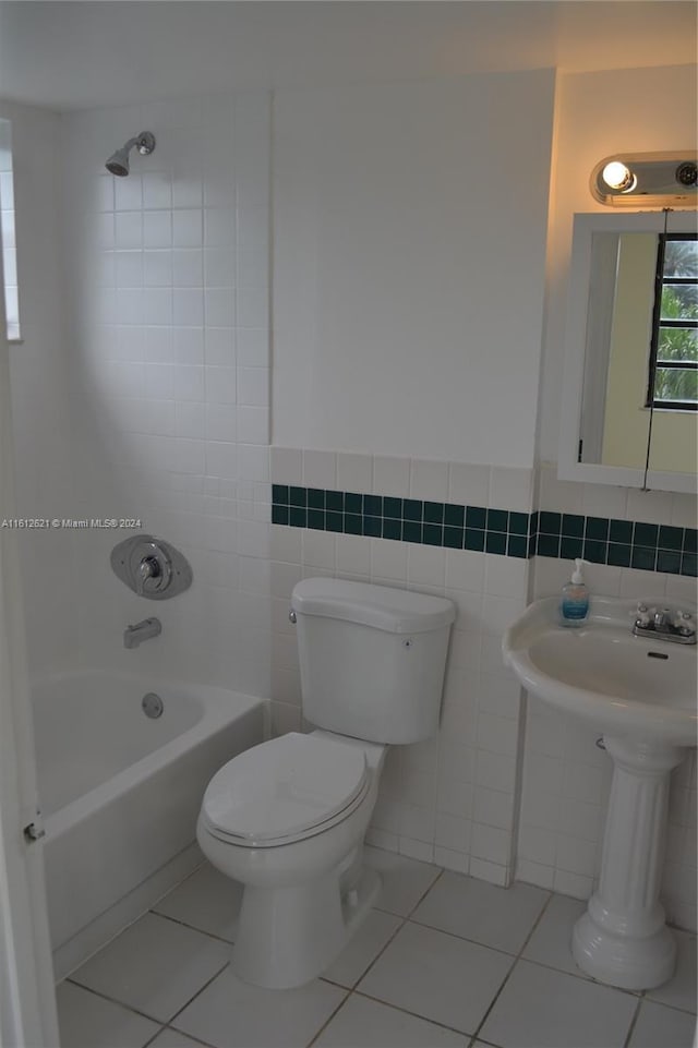 bathroom featuring tile patterned flooring, tiled shower / bath, tile walls, and toilet