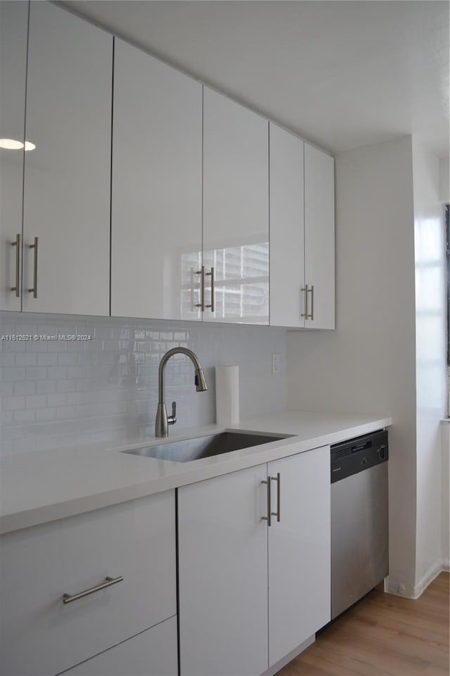 kitchen featuring white cabinetry, dishwasher, sink, and light hardwood / wood-style flooring