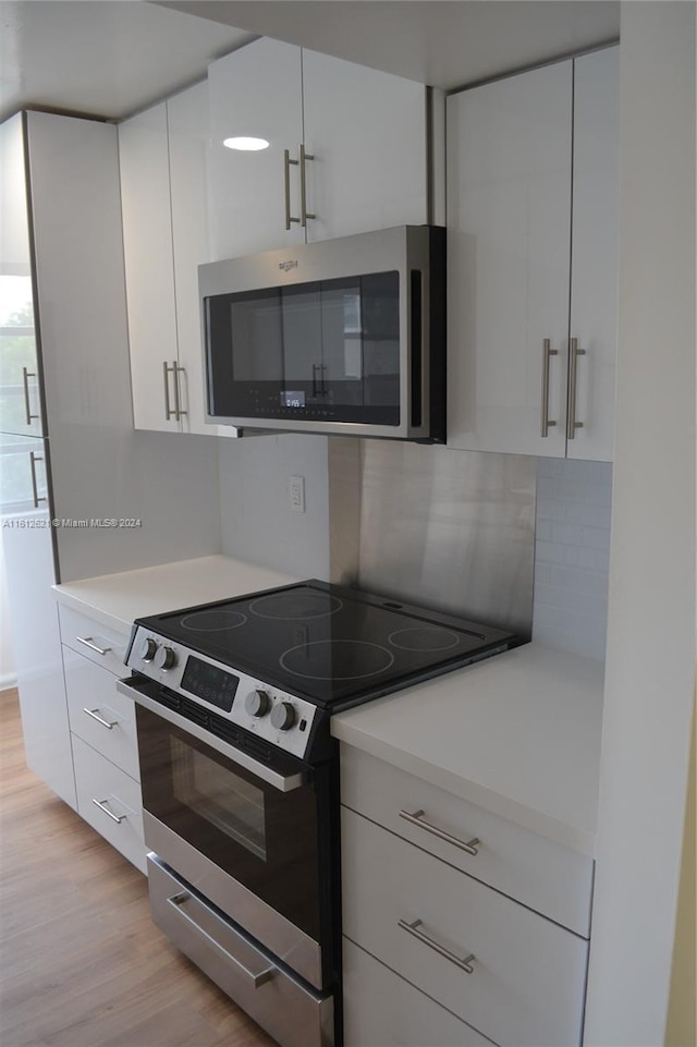 kitchen featuring white cabinetry, appliances with stainless steel finishes, decorative backsplash, and light hardwood / wood-style flooring